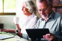 Elderly couple navigate opting out of Winter Fuel Payment on Ipad.