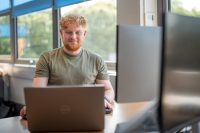 Matthew Jackson, Associate Director of Small Business at Old Mill, works on computer at desk in office space.