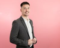 George Gillman, Associate Adviser at Old Mill, wearing dark suit in front of pink wall.